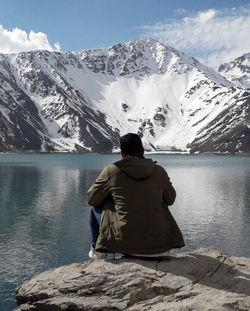 Rear view of man looking at lake against mountain range