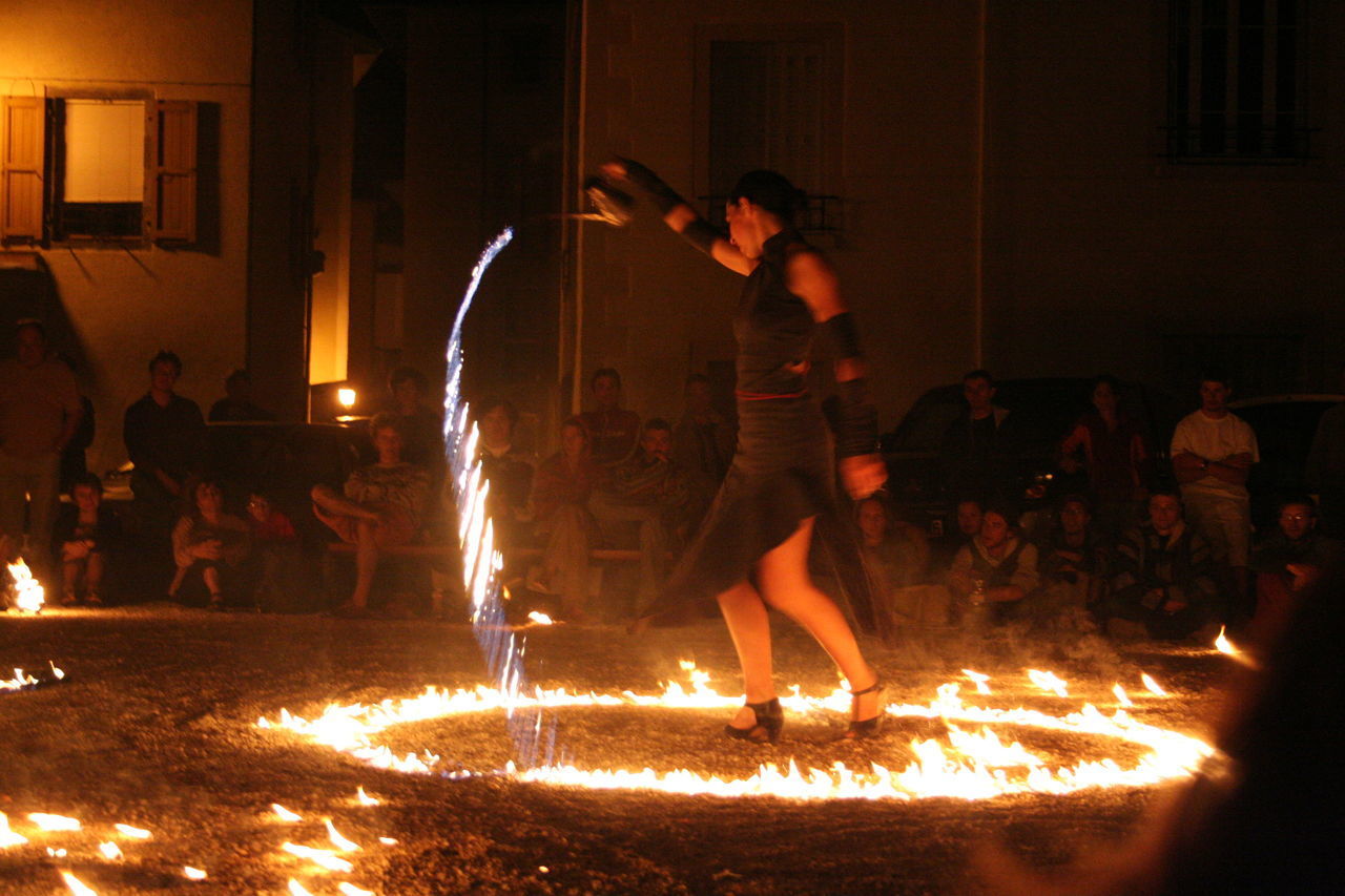 PEOPLE STANDING BY ILLUMINATED FIRE AT NIGHT DURING SUNSET