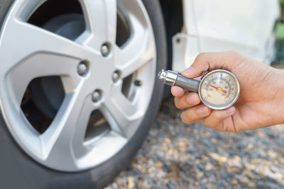 Cropped hand of person checking air pressure of car tire