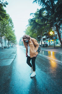 Full length of woman standing on street in rain