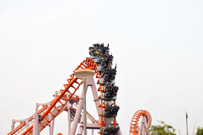 Low angle view of people enjoying rollercoaster ride at amusement park against clear sky