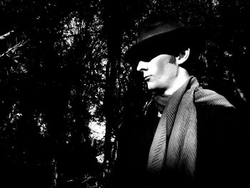 Portrait of young man looking away against trees