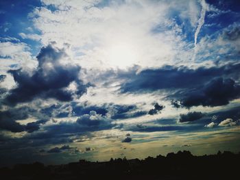 Low angle view of silhouette trees against dramatic sky
