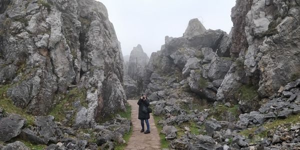 Rear view of man standing on rocks against mountains