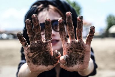 Close-up of woman showing dirty hands at beach