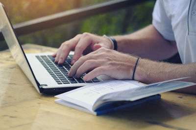 Close-up of man using laptop on table