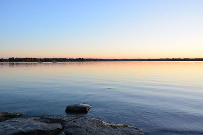 Scenic view of lake against clear sky during sunset