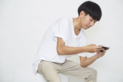 Young man using mobile phone against white background