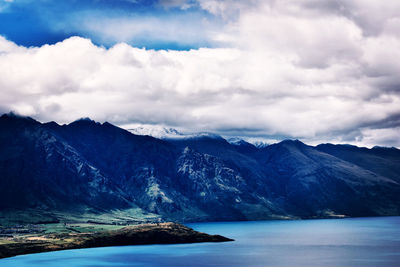 Scenic view of lake by mountains against sky