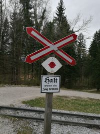 Information sign on road by trees against sky