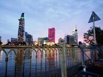 Bridge over river by buildings against sky in city