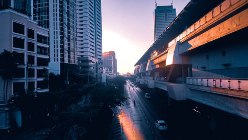 Traffic on road amidst buildings in city during sunset