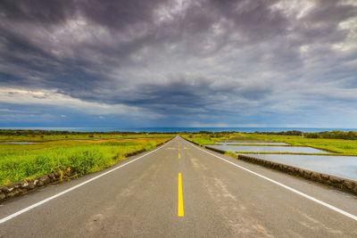 Road amidst field against sky