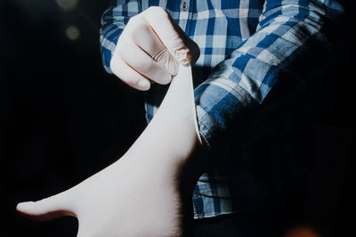 Midsection of man holding paper while standing at home