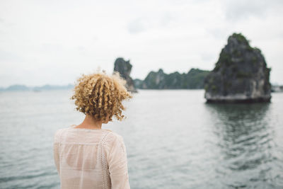 Rear view of woman looking at sea against sky