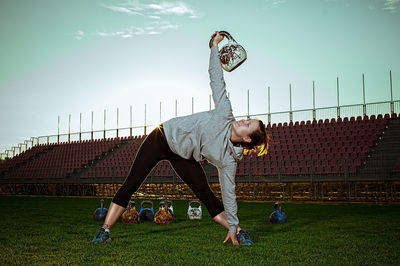 Full length of woman lifting kettlebell at stadium