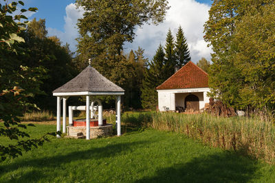 House amidst trees and plants on field against sky