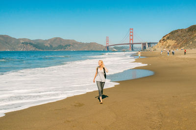 Woman walking at beach against clear sky