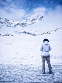 Full length rear view of woman standing on frozen lake against snow covered mountains