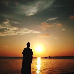 Silhouette man looking at sea against sky during sunset