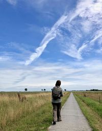 Rear view of woman walking on footpath against sky