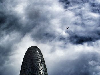 Low angle view of airplane flying against cloudy sky