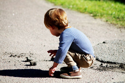 Full length of boy crouching on street