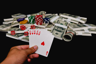 Cropped image of man holding cards while playing poker over black background