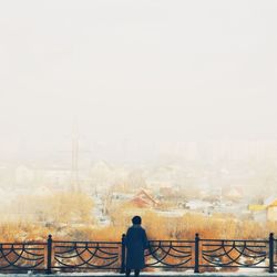 Rear view of silhouette man and cityscape against clear sky