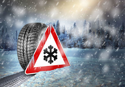 Close-up of road sign and tire on snowy field