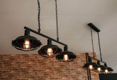 Low angle view of illuminated pendant lights hanging on wall