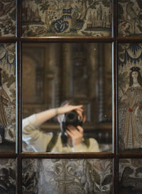 Self-portrait of a woman holding the camera in front of an antique mirror with  medieval tapestry 