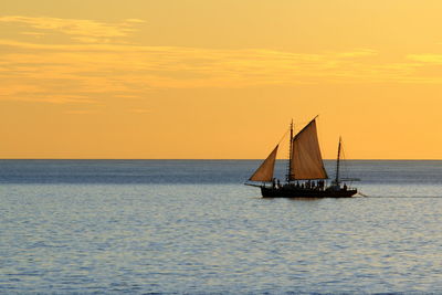 Sailboat sailing on sea against sky during sunset