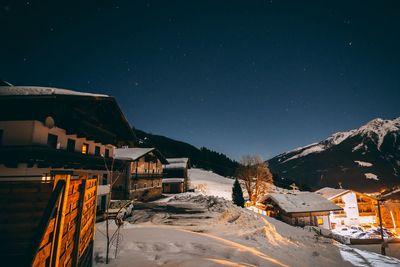 Houses on snow covered landscape against sky at night