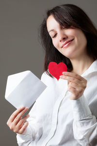 Midsection of woman holding heart shape against white background