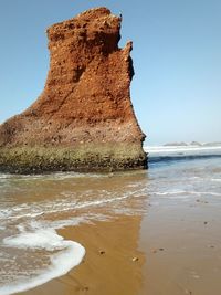 Rock formation on beach against clear sky