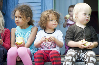 Children sitting on steps and eating apples