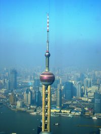 Communications tower in city against sky