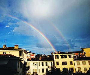 Rainbow over buildings in city against sky