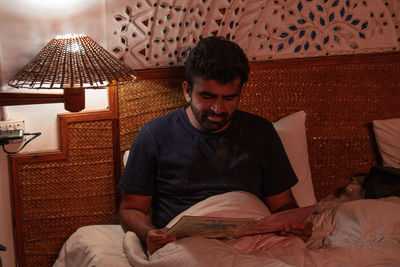 Young man sitting on bed at home