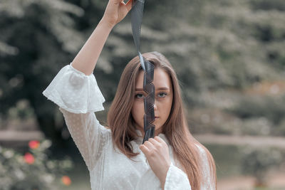 Portrait of woman with arms raised standing outdoors