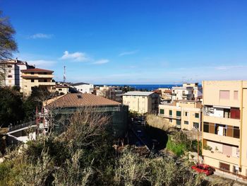 High angle view of buildings in city against blue sky