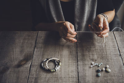 High angle view of woman making bracelets at table