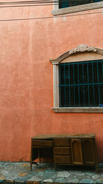 Empty bench against brick wall of old building