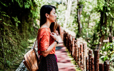 Side view of young woman looking away in forest