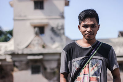 Portrait of young man standing against building