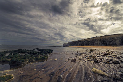 Scenic view of beach against cloudy sky