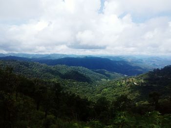 View of lush green landscape against cloudy sky