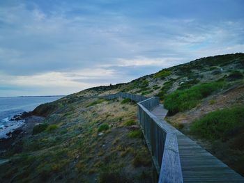 Scenic view of sea by mountain against sky