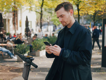 Young man unlocking electric push scooter in city